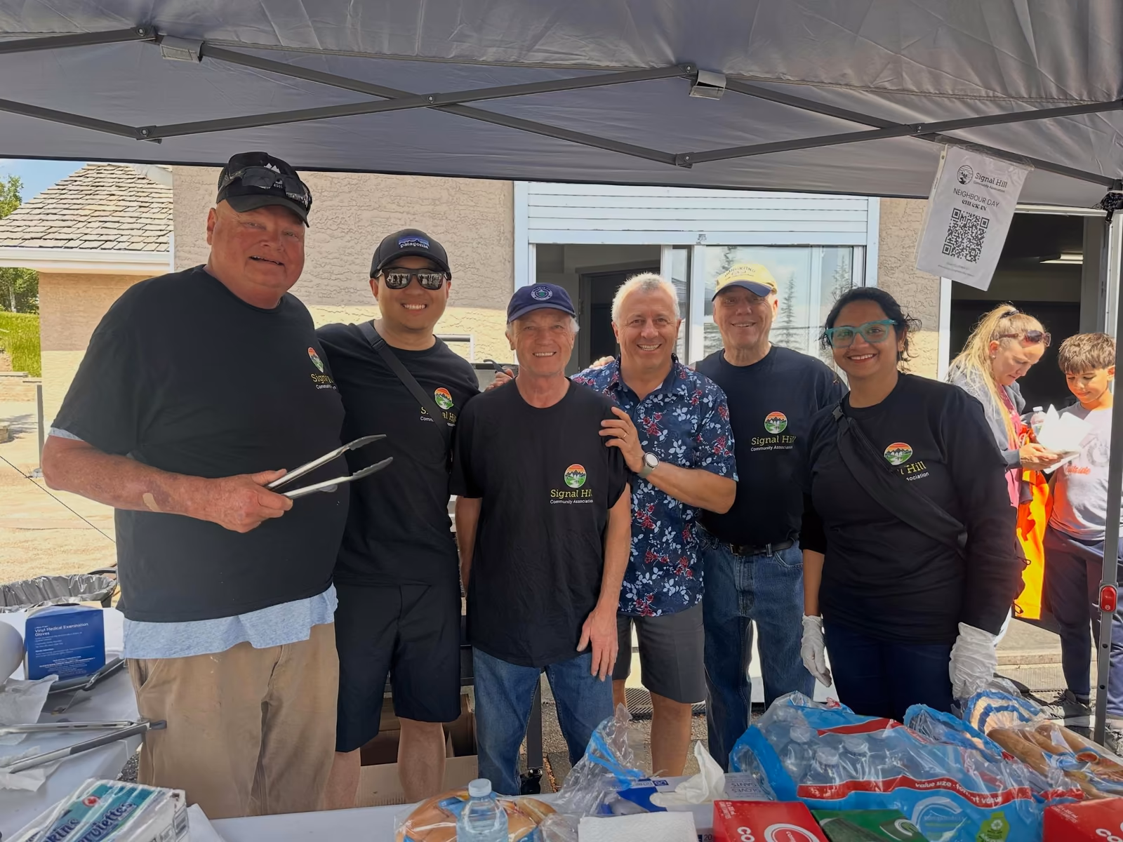 The Neighbour Day volunteer and board crew gathered behind the BBQ